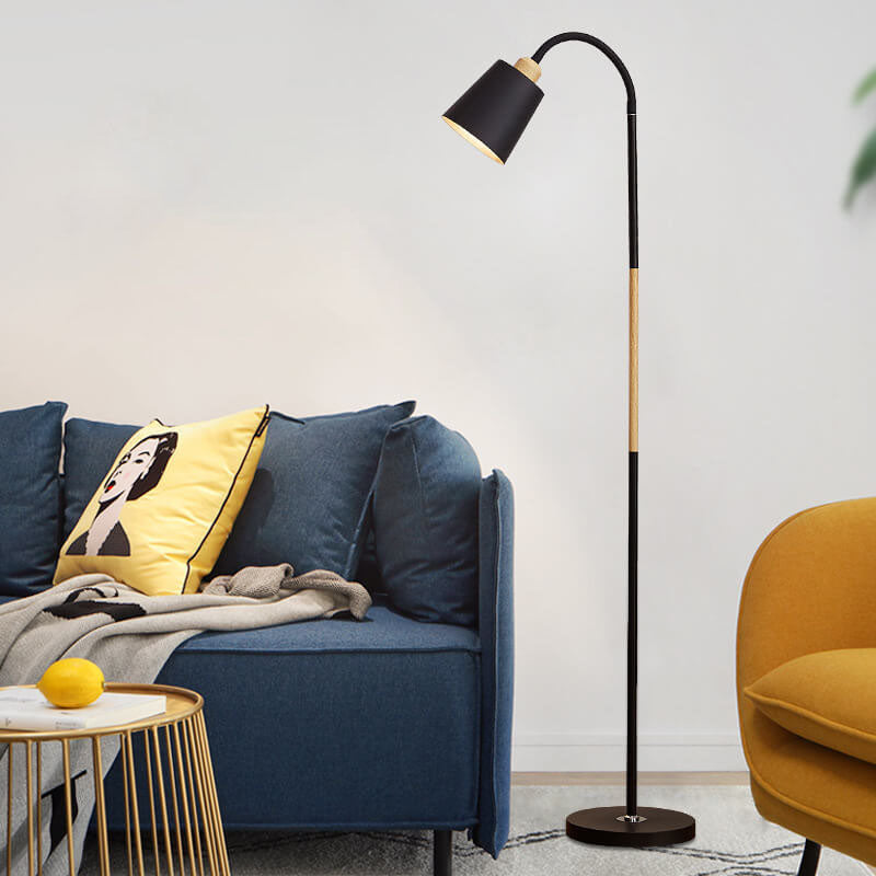 Schwarze Stehlampe mit Holzstab neben blauem Sofa und gelbem Kissen