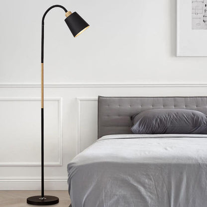 Schwarze Stehlampe mit hellem Holzdetail neben Bett und Wandbild