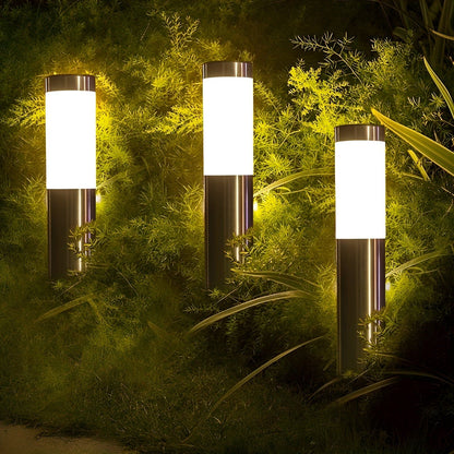 Vier LED-Gartenleuchten mit Edelstahlkörper strahlen hell inmitten von Büschen