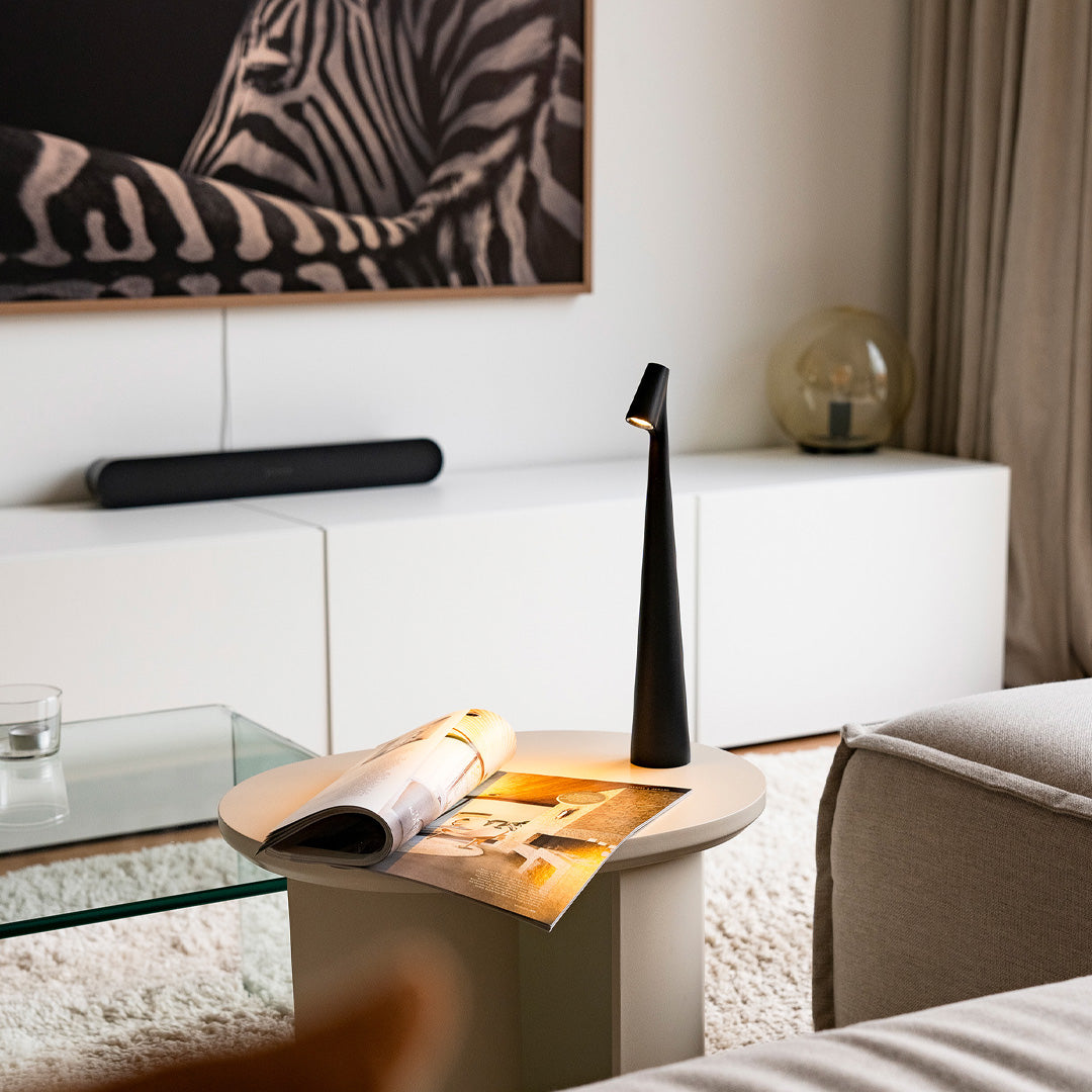 Schwarze Designerlampe auf Wohnzimmertisch neben Sofa