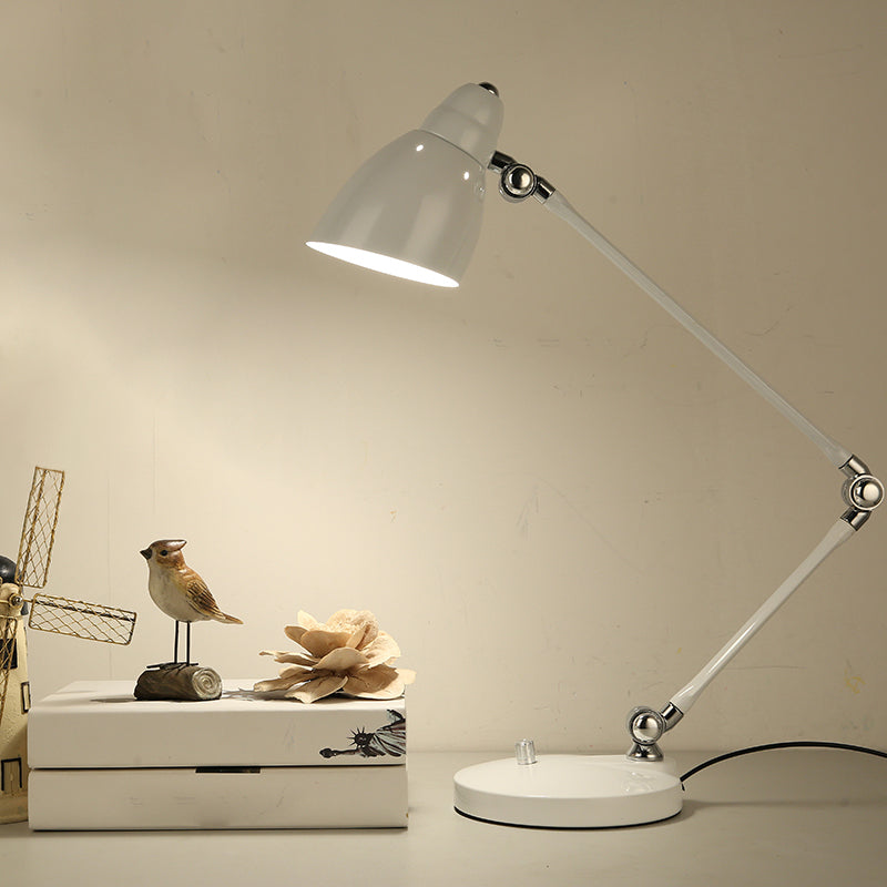 Weiße Schreibtischlampe mit schwenkbarem Arm auf einem Nachttisch neben Deko-Vogel