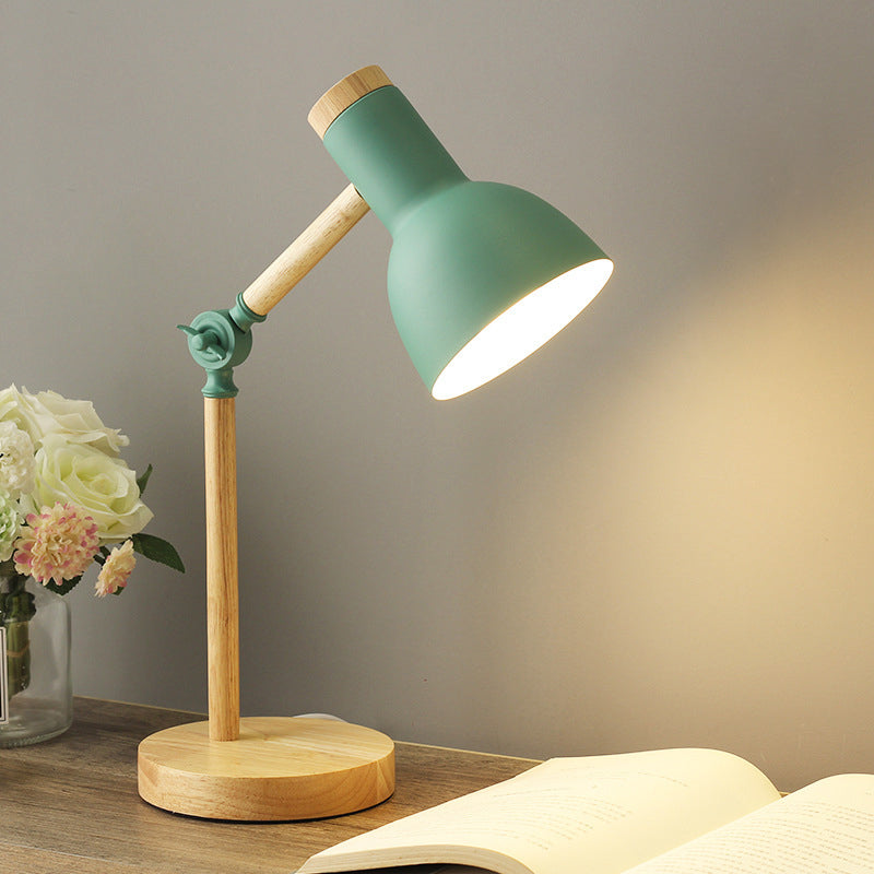Mintgrüne Lampe mit Holzdetails und verstellbarem Arm auf Tisch neben Blumen