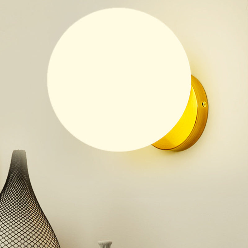 Kugelförmige Wandleuchte mit warmweißem Licht auf goldenem Sockel