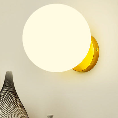 Kugelförmige Wandleuchte mit warmweißem Licht auf goldenem Sockel