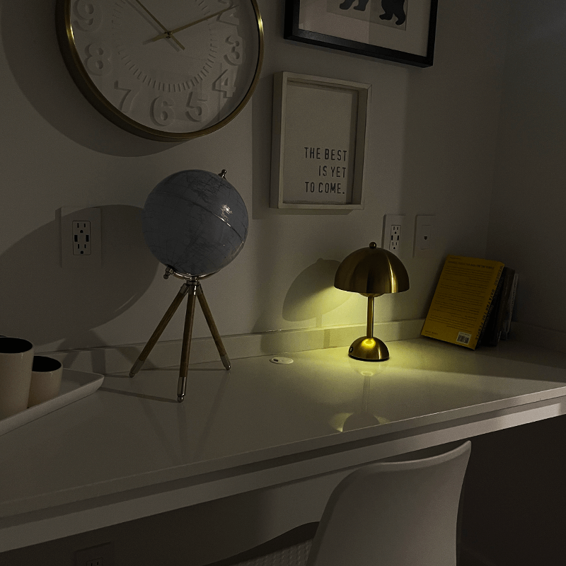 Graue Tischlampe mit goldenem Lichtschein auf weißem Schreibtisch