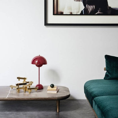 Rote Designlampe auf Beistelltisch neben grünem Sofa