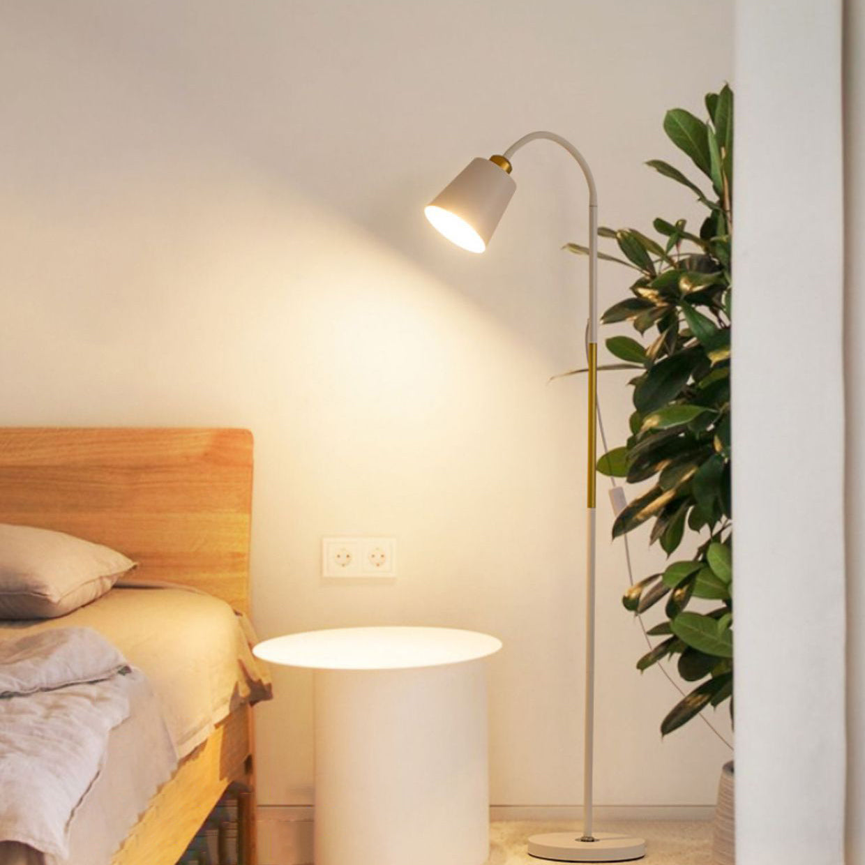 Weiße Stehlampe mit Holzakzent neben Bett und rundem Nachttisch