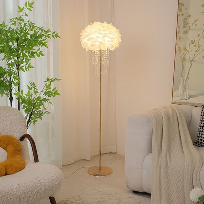 Feder-Stehlampe mit goldenem Fuß in hellem Wohnzimmer neben einem Rattanstuhl