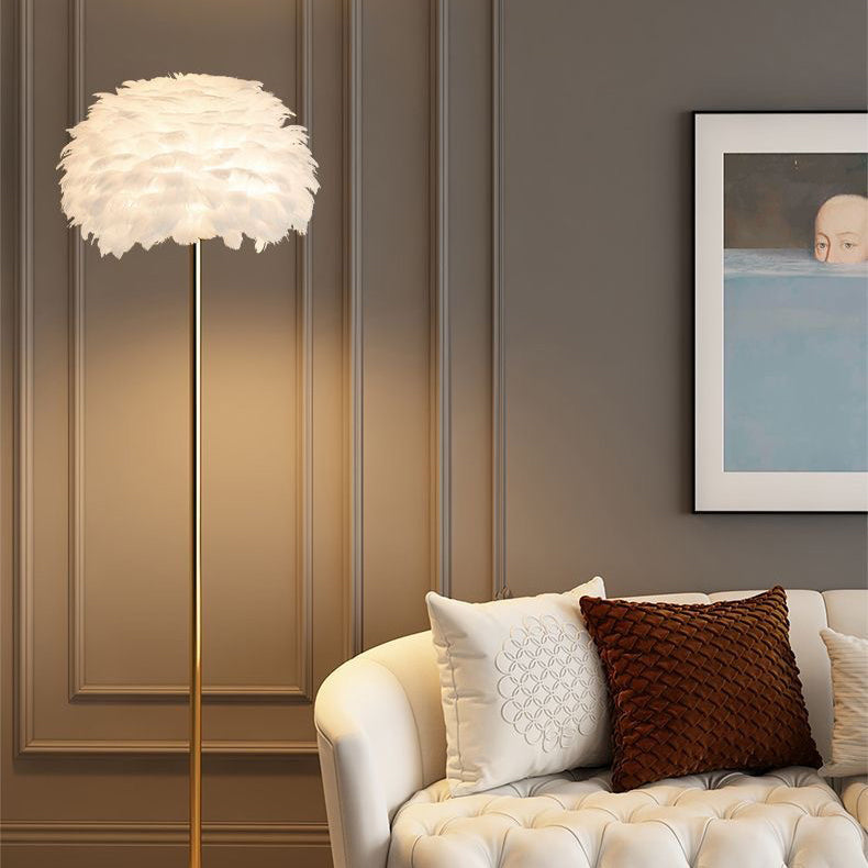 Weiße Stehlampe mit Feder-Design neben Sofa mit Kissen in elegantem Wohnzimmer