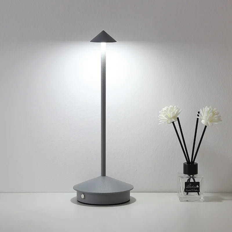Graue LED-Tischlampe mit schmalem Design auf weißem Tisch