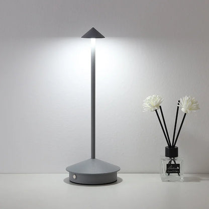Graue LED-Tischlampe mit schmalem Design auf weißem Tisch