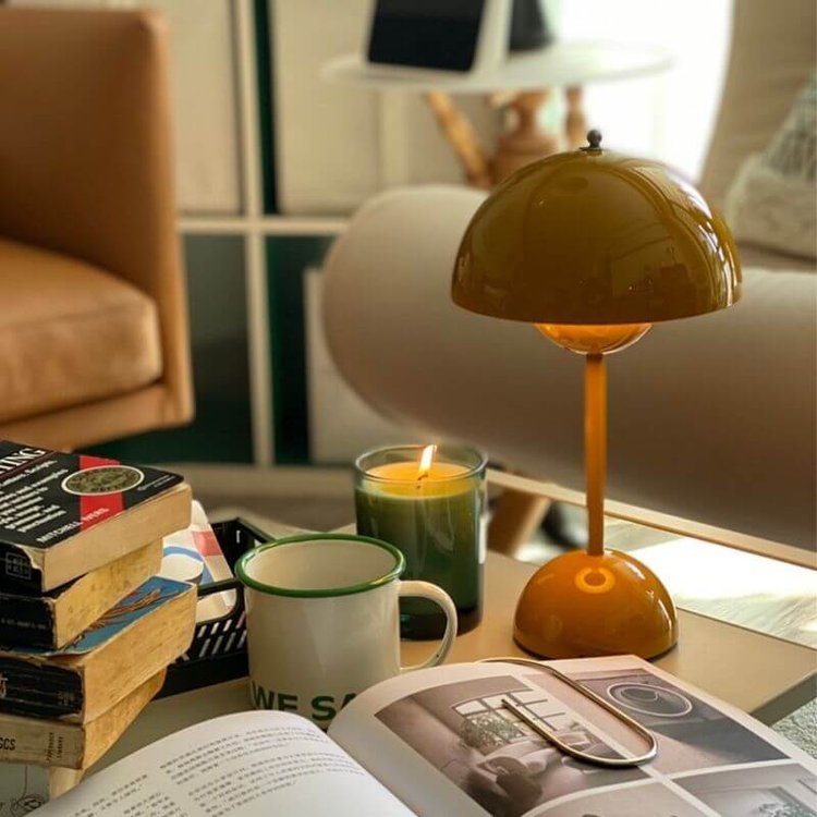 Orange Lampe auf Tisch mit Bücherstapel und Zeitschriften