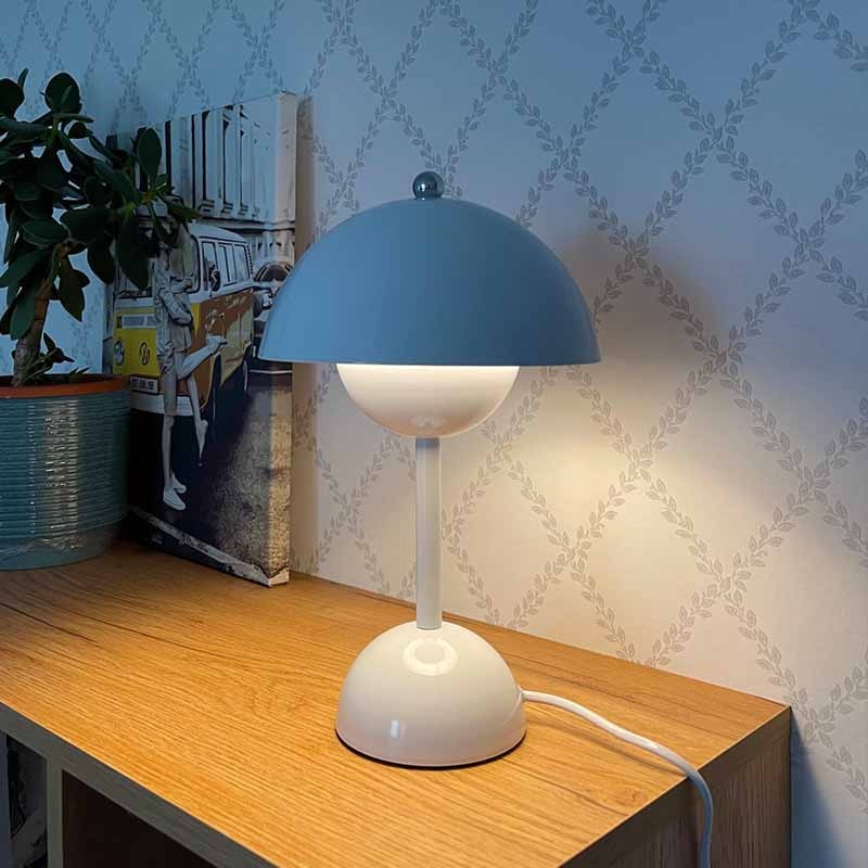 Weiß-blaue Retro-Tischlampe auf Holzschreibtisch mit Tapetenhintergrund
