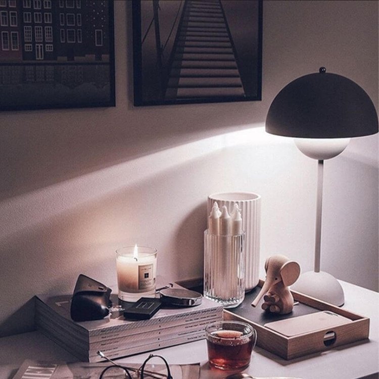 Schwarze Tischlampe leuchtet über Kerzen auf Holztablett